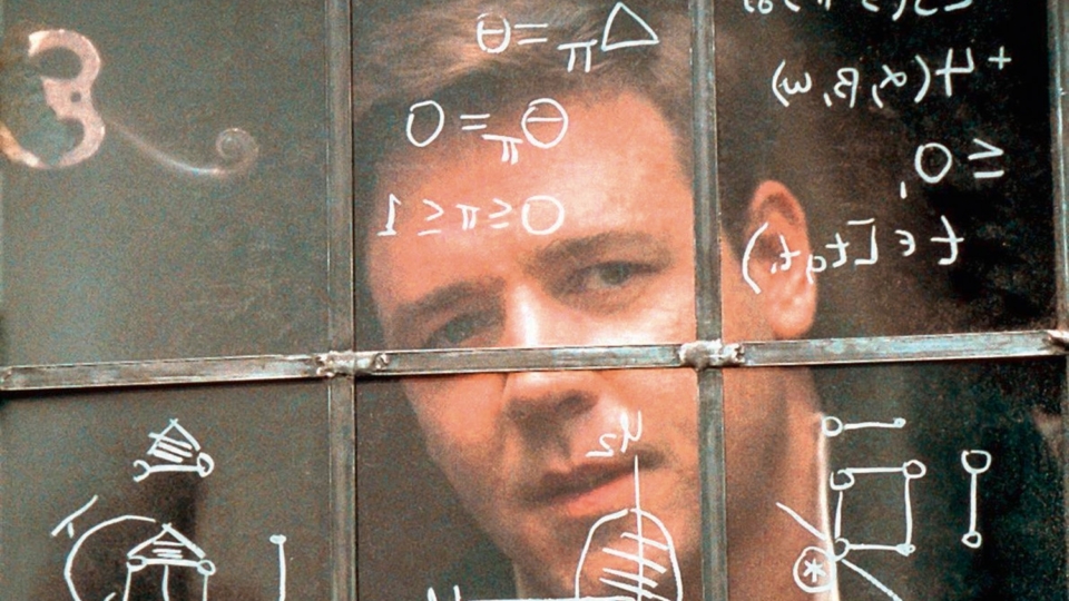 młody mężczyzna z palcem przy skroni skupiony na liczeniu w pamięci przed tablicą