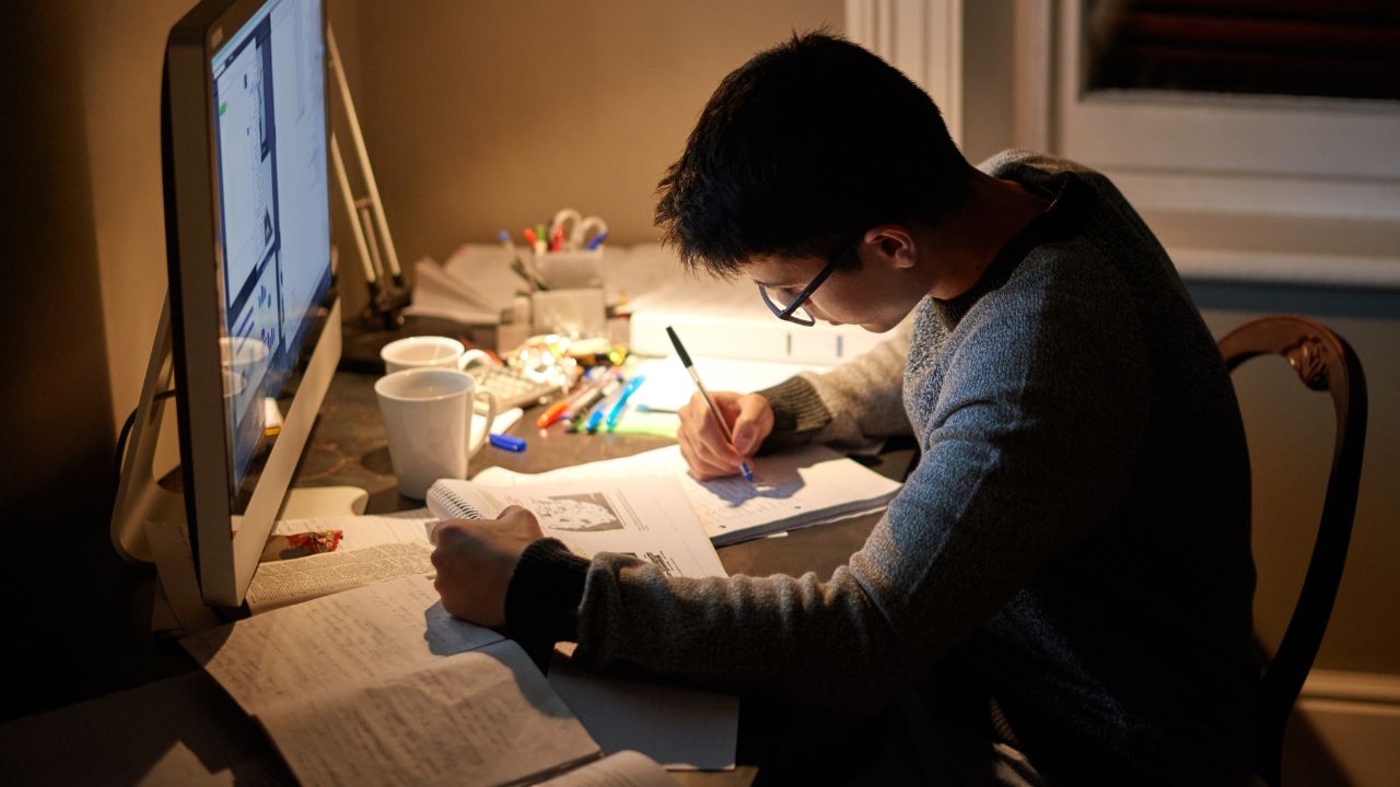 zmęczony student śpiący z głową na poduszce obok książek